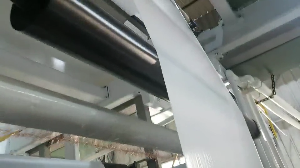 Light-coloured web passing over a large roller in the machine