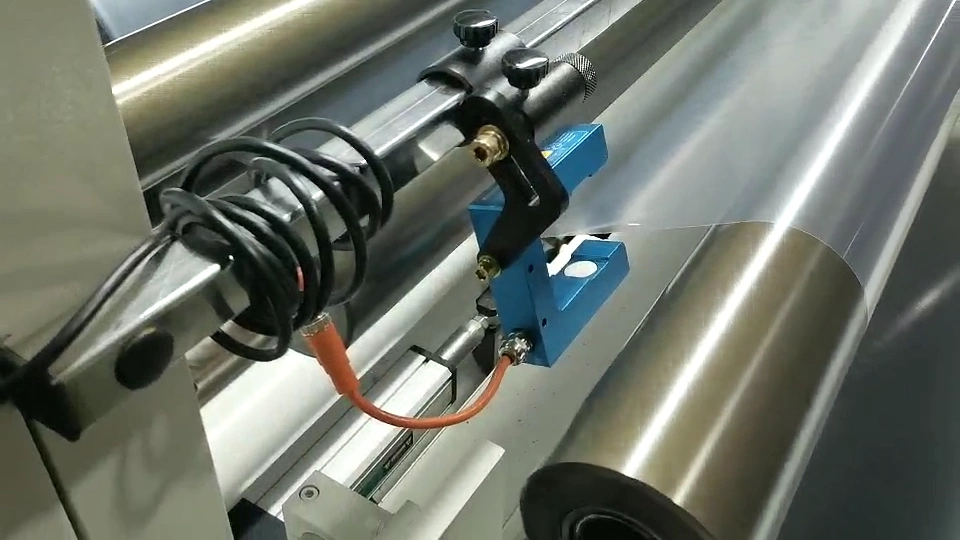 Blue sensing head and mounting support positioned beside a reflective web at a roller