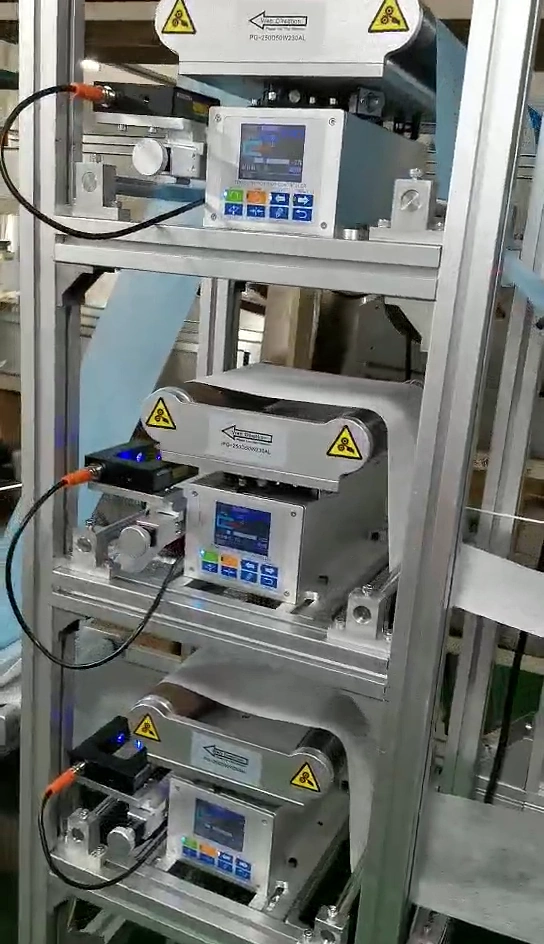 Three vertically stacked guide stations with rollers, local control panels and blue and white webs